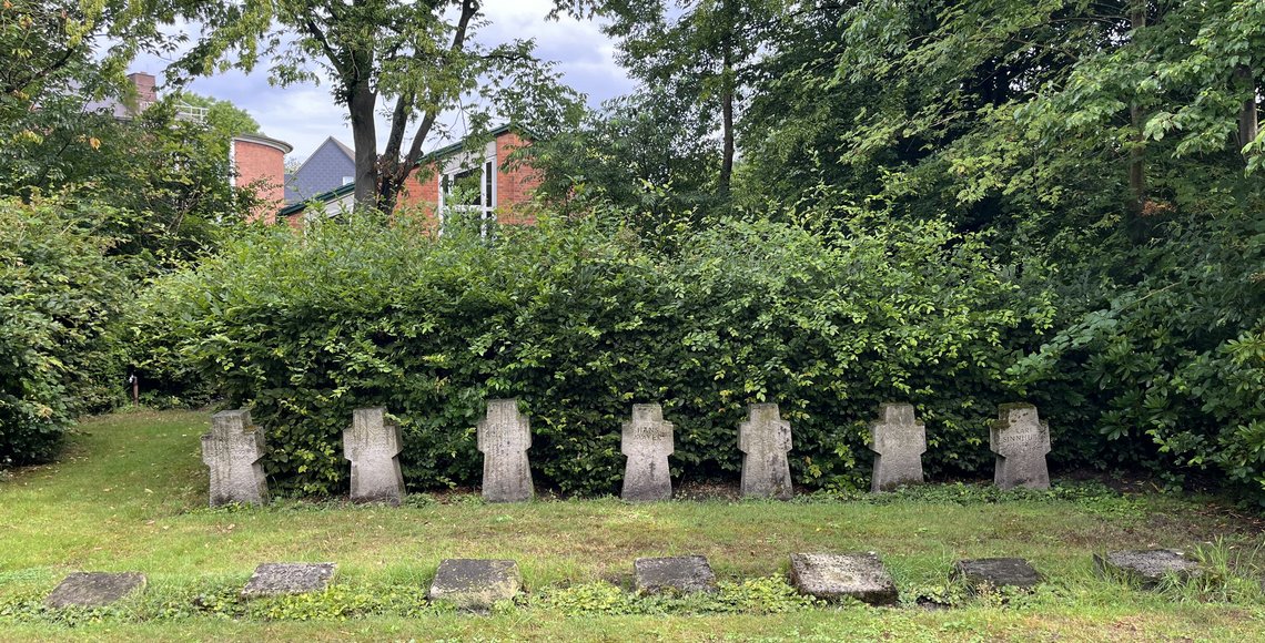 Verwitterte Grabkreuze und Steinplatten der Kriegstoten