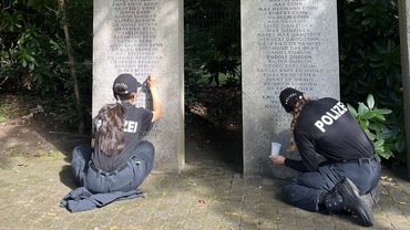 Zwei Polizistinnen malen verblasste Namen nach