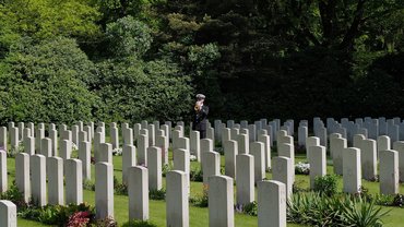 Ein Trompeter steht zwischen weißen Grabsteinen